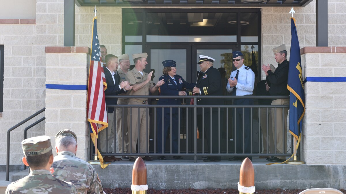 U.S. Air Force Col. Angelina Maguinness, 17th Training Wing Commander, and U.S. Navy Lt. Cmdr. Nicholas Leyba Center for Information Warfare Training Command Monterey, Detachment Goodfellow Headquarters commander shake hands upon completion of the Navy Ribbon Cutting Ceremony at Goodfellow Air Force Base Feb. 2, 2024. Due to a cold front in the winter of 2021, the original building was out of code and needed renovation; it was soon demolished. They renovated another building and decided to add a wing, which is now the headquarters quarterdeck/entryway, training room, gym, and additional office space. (U.S. Air Force photo by 2nd Lt. Kayunna Holt)
