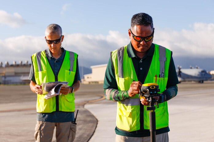 Joven Cadiz, right, civil engineer technician, and Greg Murakami, left, airfield pavement inspection lead, Civil Engineering Branch, Naval Facilities Engineering Systems Command Pacific, inspect the taxiway area of Marine Corps Air Station Kaneohe Bay during an airfield inspection, Marine Corps Base Hawaii, Jan. 25, 2024. This inspection occurs every 3 years and serves to provide detailed information for the sustainment and maintenance of the airfield. (U.S. Marine Corps photo by Sgt. Brandon Aultman)