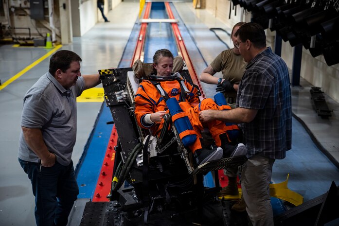 An Air Force Research Laboratory, or AFRL, team and NASA prepare a U.S. Air Force volunteer on the horizontal sled test facility at Wright-Patterson Air Force Base, Ohio, Oct. 23, 2023, to test the next replica of a seat and flight suit for the Orion space capsule. Researchers with the AFRL Human Effectiveness Directorate tested equipment for the Orion space capsule’s upcoming mission to the moon. (U.S. Air Force photo / Richard Eldridge)