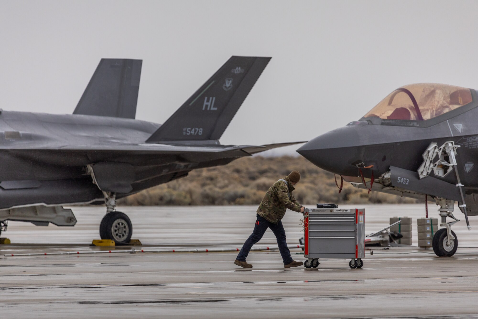 a photo of an F-35 maintainer pushing a toolbox on the flightline