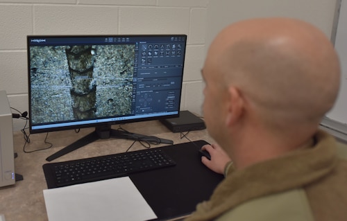 An Airman looks at a monitor displaying data from a microscope