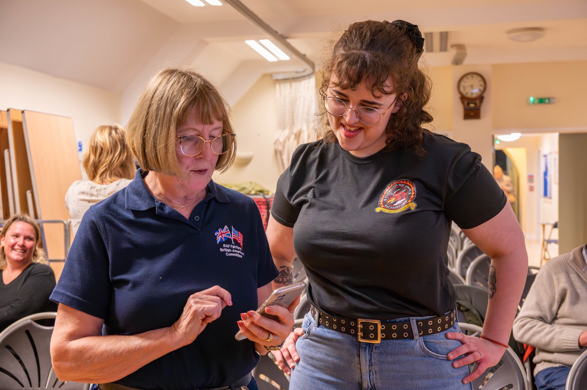 A member of the British-American Committee speaks with a member of the 99th Expeditionary Reconnaissance Squadron.