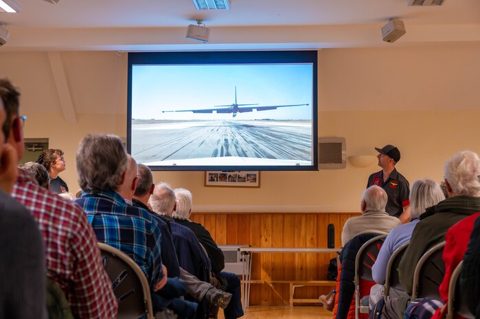 Members of the local community watch a video of a U-2 Dragon Lady landing.