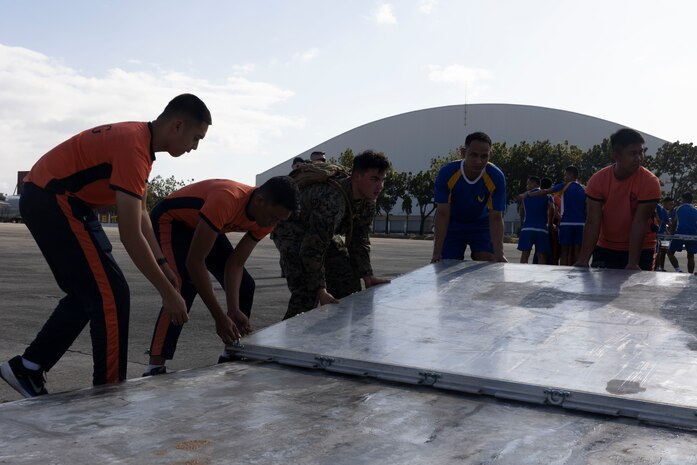 U.S. Marines with Marine Aerial Refueler Transport Squadron 152, 1st Marine Aircraft Wing, alongside Philippine military and coast guard service members position pallets to secure Department of Social Welfare and Development family food packs in preparation for transportation at Villamor Airbase, Pasay City, Philippines, Feb. 11, 2024. At the request of the Government of the Philippines, the U.S. Marines of III Marine Expeditionary Force are supporting the U.S. Agency for International Development in providing foreign humanitarian assistance to the ongoing disaster relief mission in Mindanao. The forward presence and ready posture of III MEF assets in the region facilitated rapid and effective response to crisis, demonstrating the U.S.’s commitment to Allies and partners during times of need. (U.S. Marine Corps photo by Sgt. Savannah Mesimer)