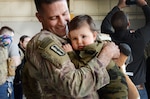 Sgt. 1st Class Jeff Stainsby, A Battery, 182nd Field Artillery, Michigan National Guard, holds his daughter, Clair, for the first time at the unit’s welcome home ceremony in Detroit, Mich, Feb. 8, 2024.