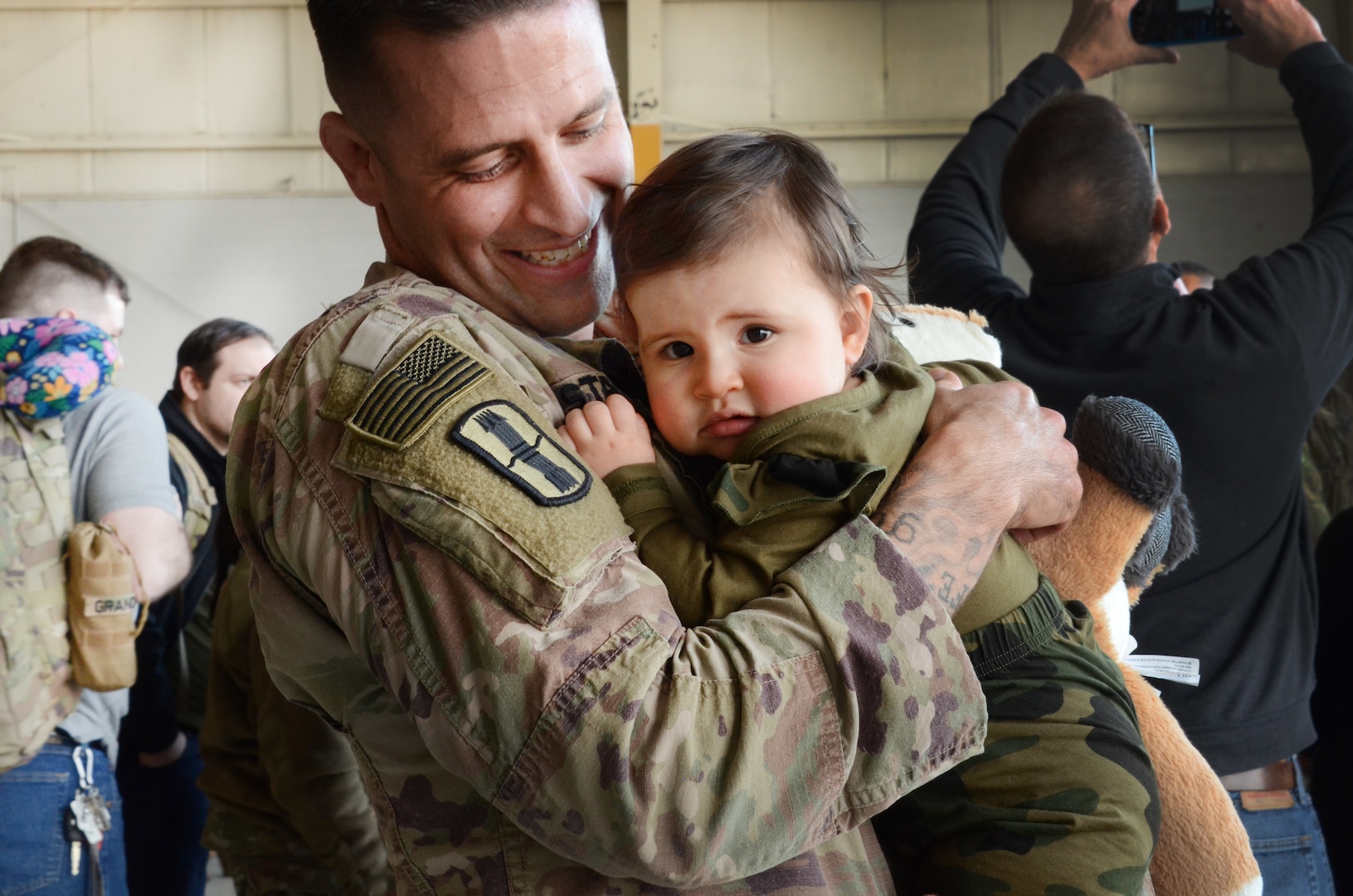 Sgt. 1st Class Jeff Stainsby, A Battery, 182nd Field Artillery, Michigan National Guard, holds his daughter, Clair, for the first time at the unit’s welcome home ceremony in Detroit, Mich, Feb. 8, 2024.