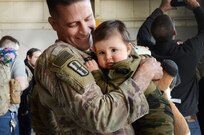 Sgt. 1st Class Jeff Stainsby, A Battery, 182nd Field Artillery, Michigan National Guard, holds his daughter, Clair, for the first time at the unit’s welcome home ceremony in Detroit, Mich, Feb. 8, 2024.