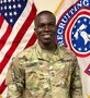 man wearing u.s. army uniform standing in front of two flags.