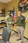 two men wearing u.s. army uniforms shake hands in a recruiting office.