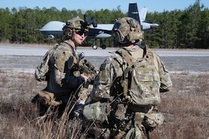 Staff Sgt Jeffrey Lewis and Tech. Sgt. Kyle Simms, 919th Special Operations Security Forces Squadron, discuss the tactics for maintaining perimeter defense at a simulated airfield overseas as an MQ-9 Reaper lands for a troop resupply mission on February 2, 2024. The MQ-9 landed on the shortest known airfield to date as part of the exercise validating a proof of concept for members of the 2nd Special Operations Squadron who fly the aircraft in support of Air Force Special Operations Command. (USAF Photo by Lt Col. James R. Wilson)