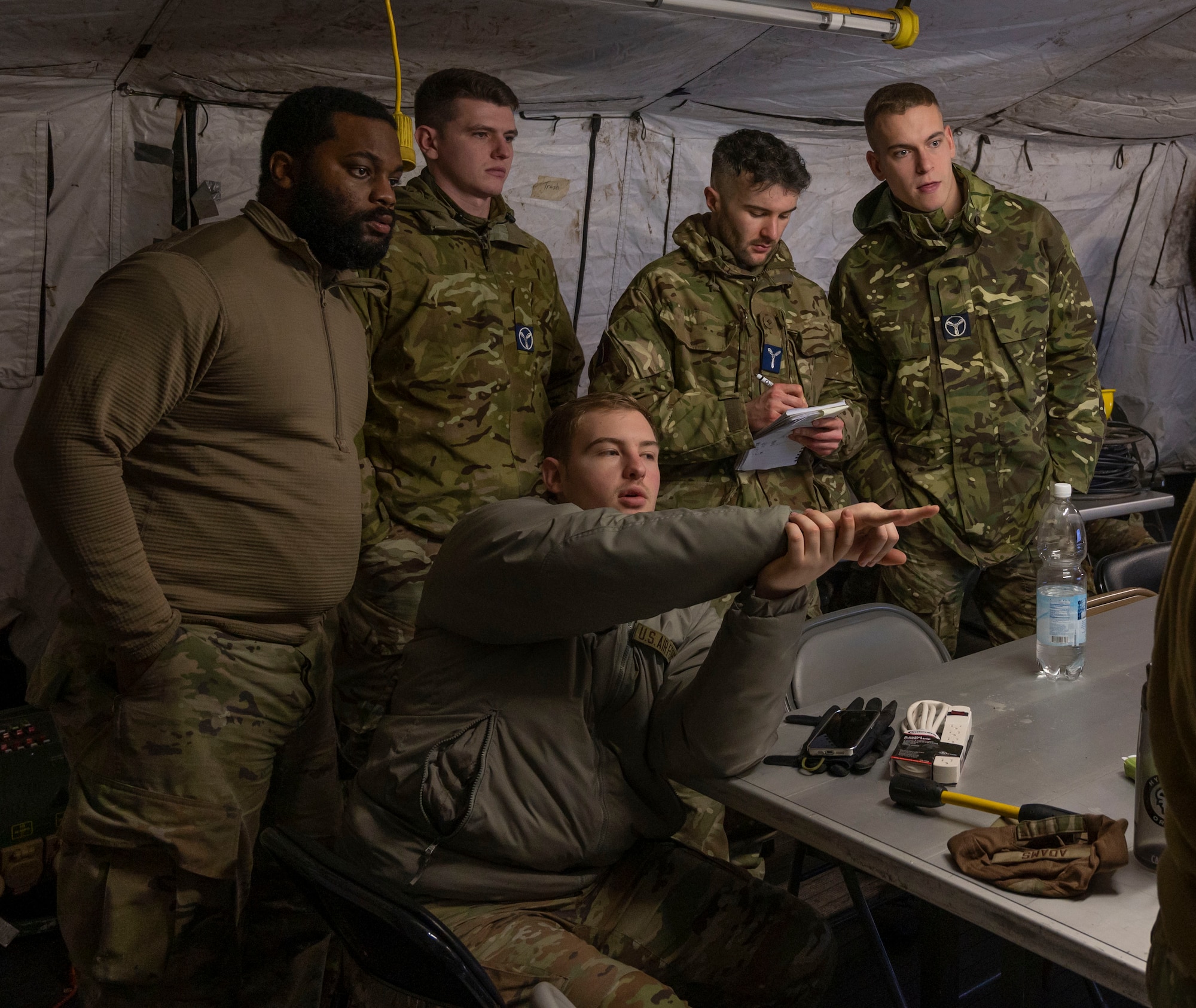 Five men observe a radio being set up