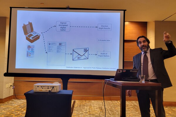 A person in a suit stands next to a projected slide presentation showing a diagram.
