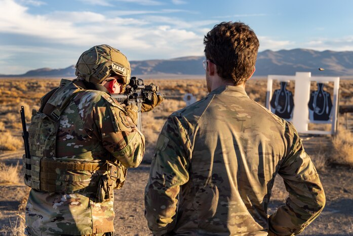 U.S. Air Force Staff Sgt. Tristen Moncel, 9th Security Forces Squadron standardization and evaluations security forces evaluator from Beale Air Force Base, California (left), fires a M-4 Carbine while an East Coast-based Naval Special Warfare Operators (SEALs) evaluates his technique at Fallon, Nevada, Jan. 30, 2024