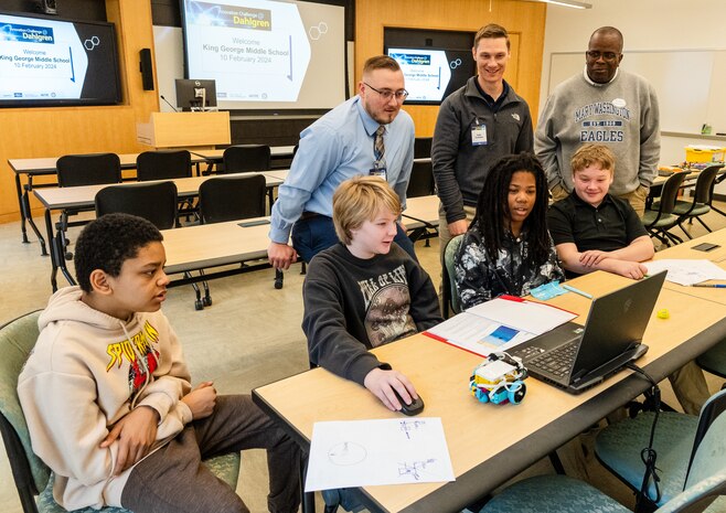 IMAGE: (Back row left to right) Naval Surface Warfare Center Dahlgren Division’s Jonathan Clark and Tyler Truslow and University of Mary Washington’s Dr. Michael Hubbard assist the King George Middle School team troubleshoot their robot during the Innovation Challenge @ Dahlgren: Middle School Robotics, Feb. 10.