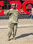 man wearing u.s. army uniform standing in an open area in a park.