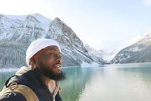 A man poses for a photo in front of a mountain landscape
