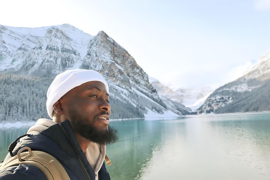 A man poses for a photo in front of a mountain landscape