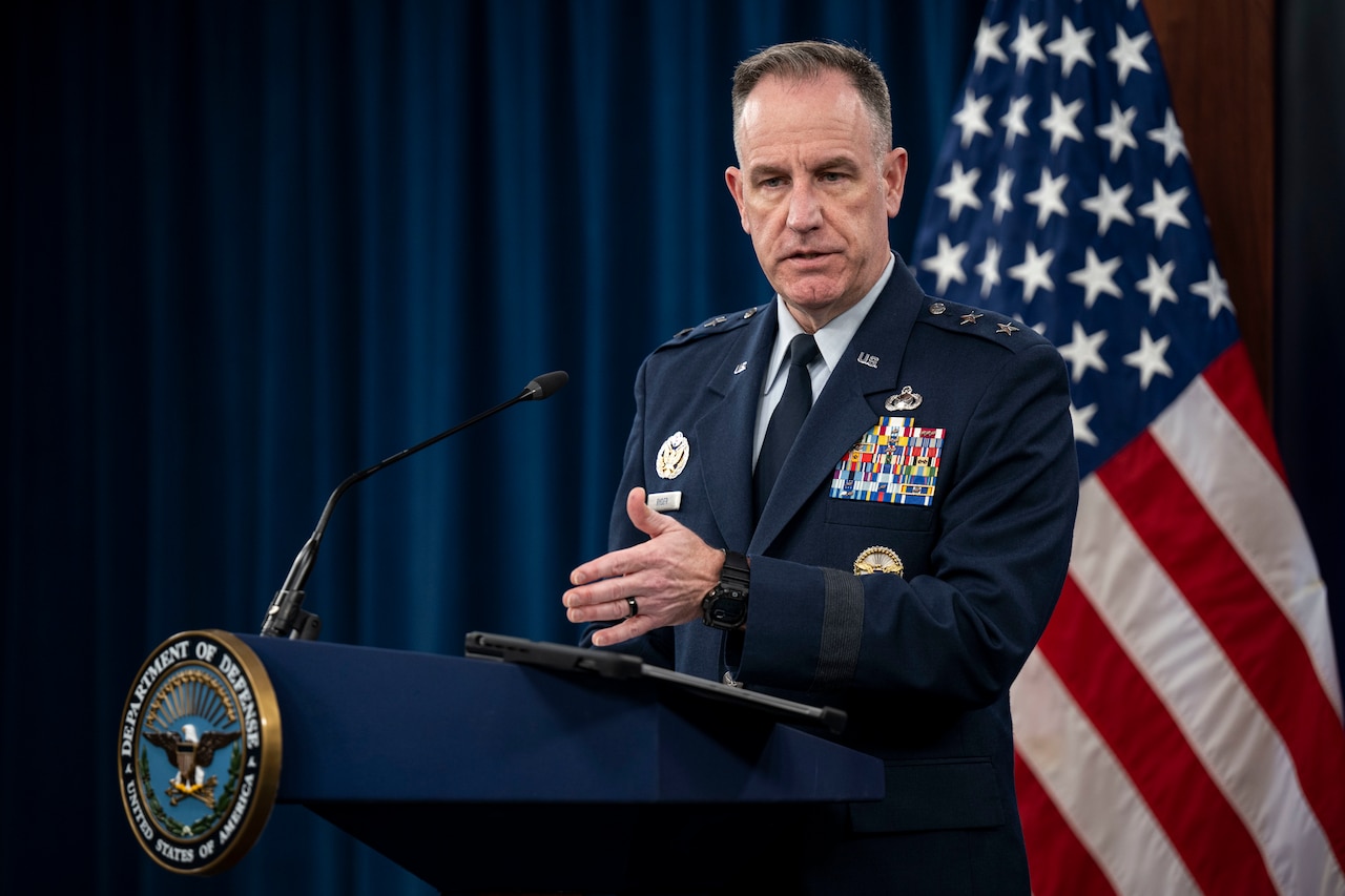 A man in military uniform stands at a lectern.