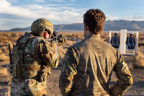 U.S. Air Force Staff Sgt. Tristen Moncel, 9th Security Forces Squadron standardization and evaluations security forces evaluator from Beale Air Force Base, California (left), fires a M-4 Carbine while an East Coast-based Naval Special Warfare Operators (SEALs) evaluates his technique at Fallon, Nevada, Jan. 30, 2024