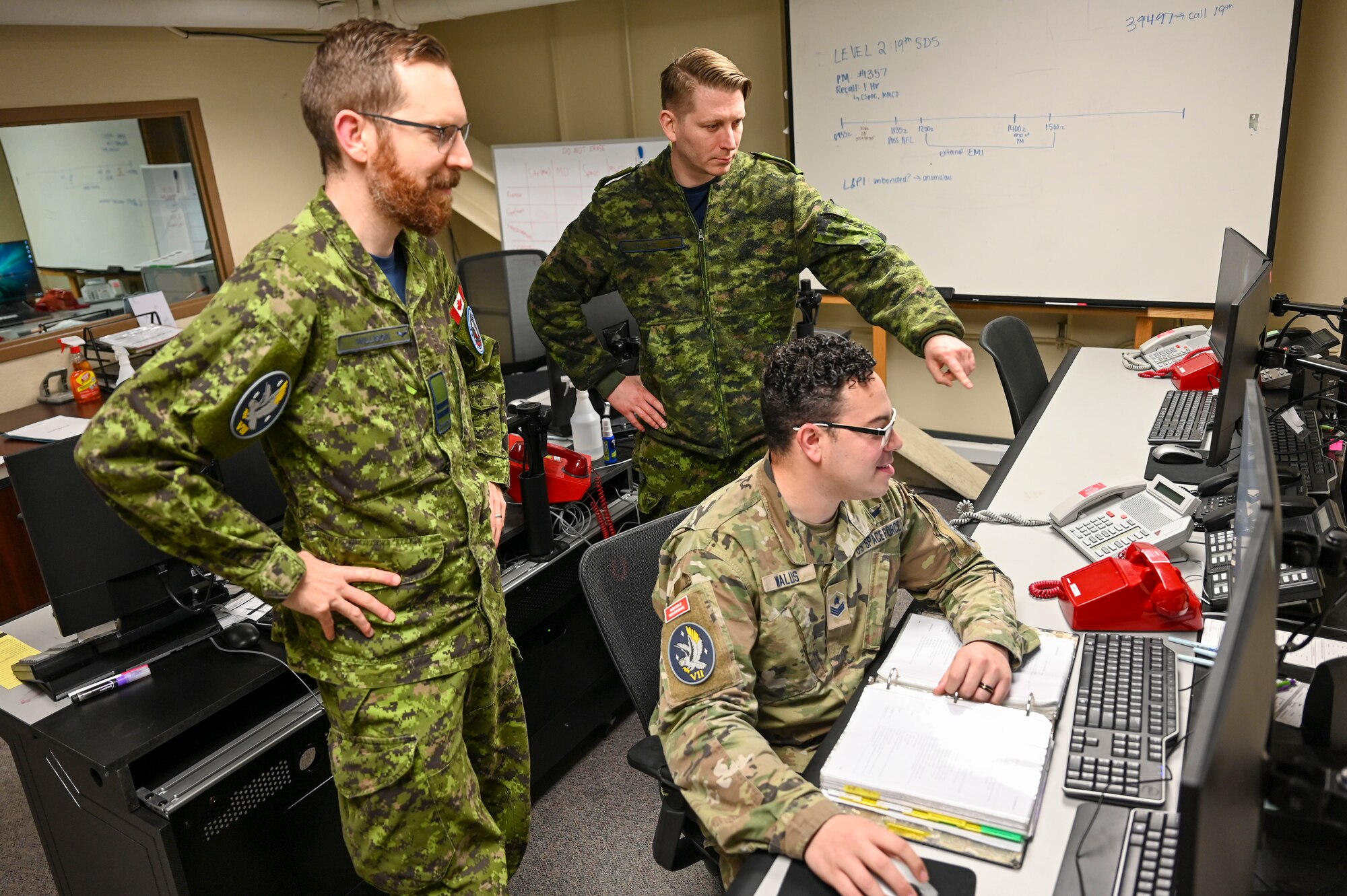 Royal Canadian Air Force Capt. Alex Willison, left, 7th Space Warning Squadron (7 SWS) commander in charge, Royal Canadian Air Force Sgt. Kristjan Lindvere, 7 SWS SNCO in charge of training, and U.S. Space Force Sgt. Dustin Wallis, 7 SWS deputy staff instructor, goes through a training simulation for the Upgraded Early Warning Radar (UEWR) on Beale Air Force Base, California, Feb. 8, 2024.