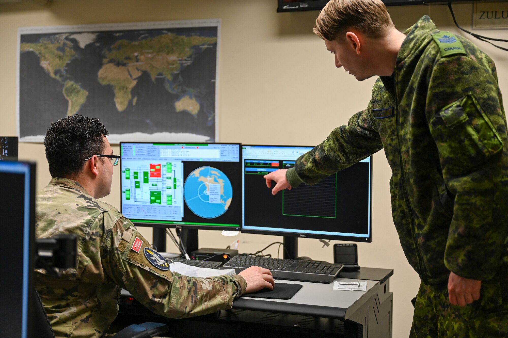 Royal Canadian Air Force Sgt. Kristjan Lindvere, right, 7th Space Warning Squadron SNCO in charge of training, and U.S. Space Force Sgt. Dustin Wallis, 7 SWS deputy staff instructor, goes through a training simulation for the Upgraded Early Warning Radar (UEWR) on Beale Air Force Base, California, Feb. 8, 2024.