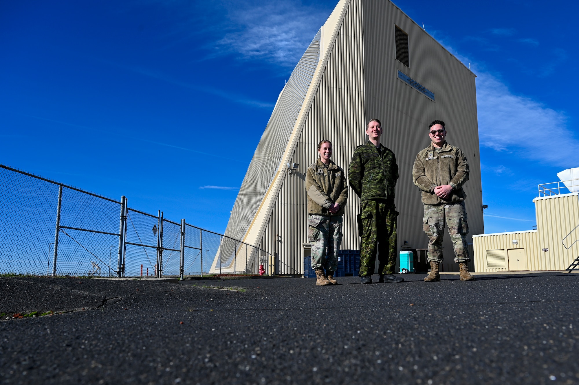 U.S. Space Force 1st Lt. Moira Huftlen, 7th Space Warning Squadron (7 SWS) student, Royal Canadian Air Force Sgt. Kristjan Lindvere, 7 SWS SNCO in charge of training, and U.S. Space Force Sgt. Dustin Wallis, 7 SWS deputy staff instructor, poses for a photo in front of the Upgraded Early Warning Radar on Beale Air Force Base, California, Jan. 11, 2024.