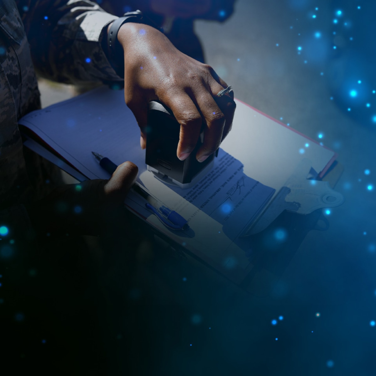 Close-up of hand with notary stamp notarizing a deploying Airman’s power of attorney over blue glitter stock background  [image is not public domain].