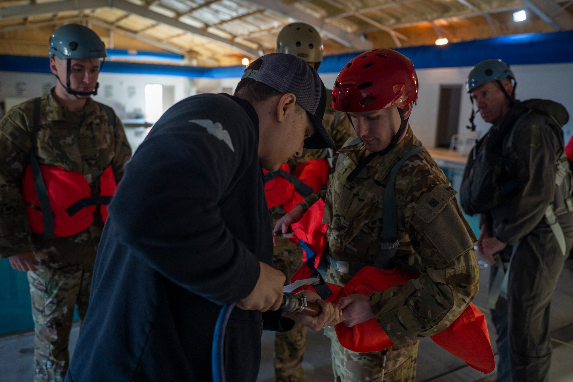 U.S. Air Force Staff Sgt. Michael Ferraro, 347th Operations Support Squadron Survival, Evasion, Resistance and Escape specialist, fills up a flotation device with air at Moody Air Force Base, Georgia, Feb. 8, 2024. Water survival training events are conducted to ensure Airmen are able to survive during a waterborne incident. (U.S. Air Force photo by Airman 1st Class Leonid Soubbotine)