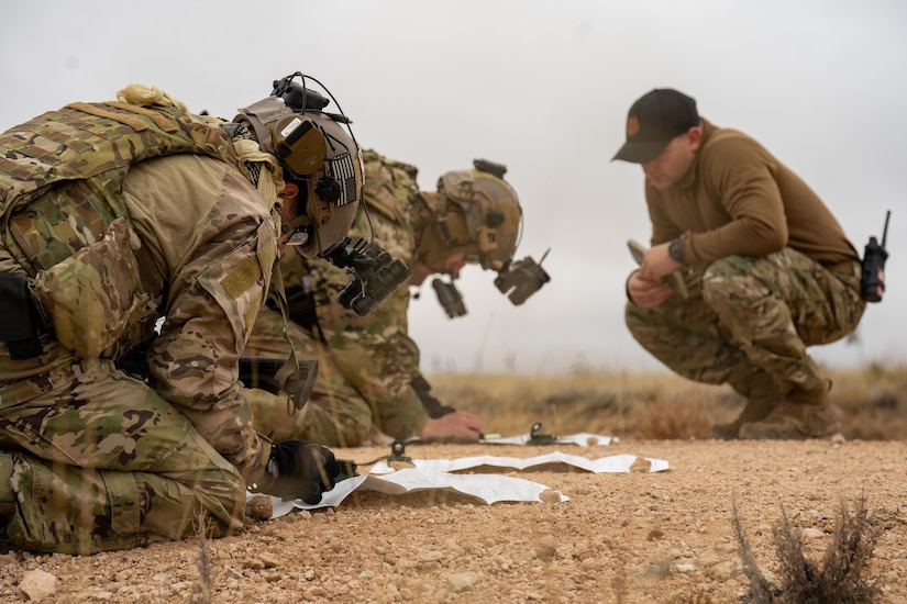 Troops in specialized training gear study land navigation documents.