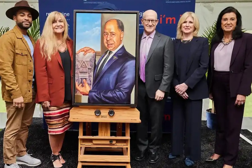 Five people stand beside an easel holding a painted portrait.