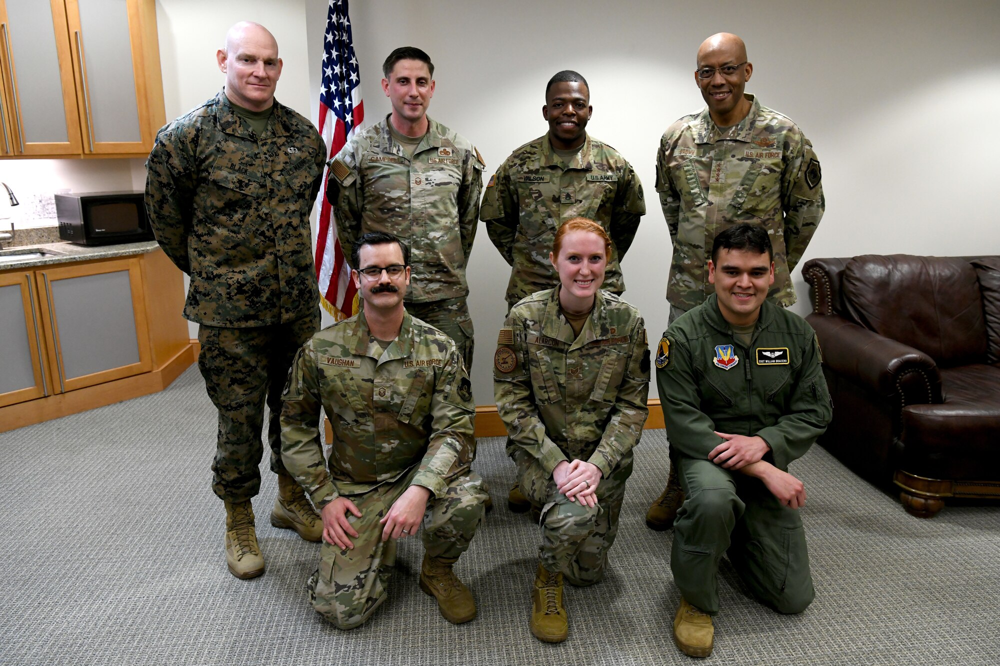 Men and women pose for a photo, four standing in the back and three kneeling in the front.