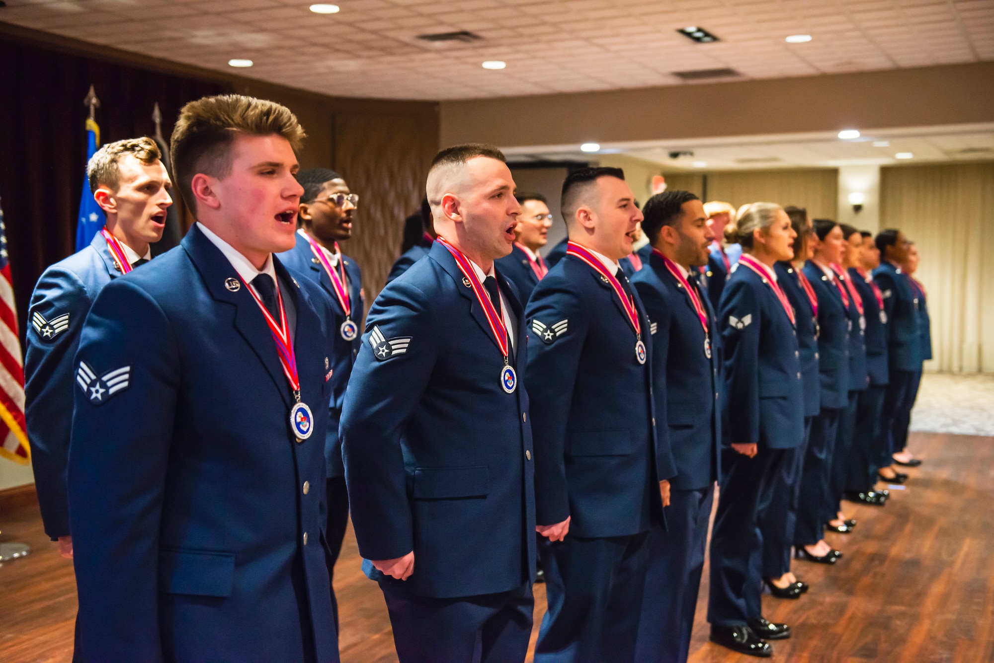 Airmen sing on a ballroom floor