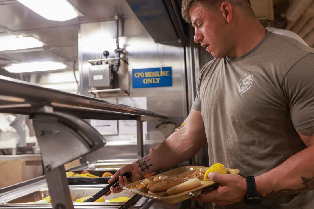 U.S. Marine Corps Sgt. Jonathan Steed, a section leader assigned to Charlie Company, Battalion Landing Team 1/5, 15th Marine Expeditionary Unit, and an Illinois native, fills his tray with food during a steel beach event aboard the amphibious transport dock USS Somerset (LPD 25) while underway in the Pacific Ocean, Feb. 4, 2024. The steel beach picnic was held to boost morale and camaraderie amongst Marines and Sailors while underway. Somerset is currently underway conducting routine operations in U.S. 3rd Fleet with elements of the 15th MEU. (U.S. Marine Corps photo by Cpl. Aidan Hekker)