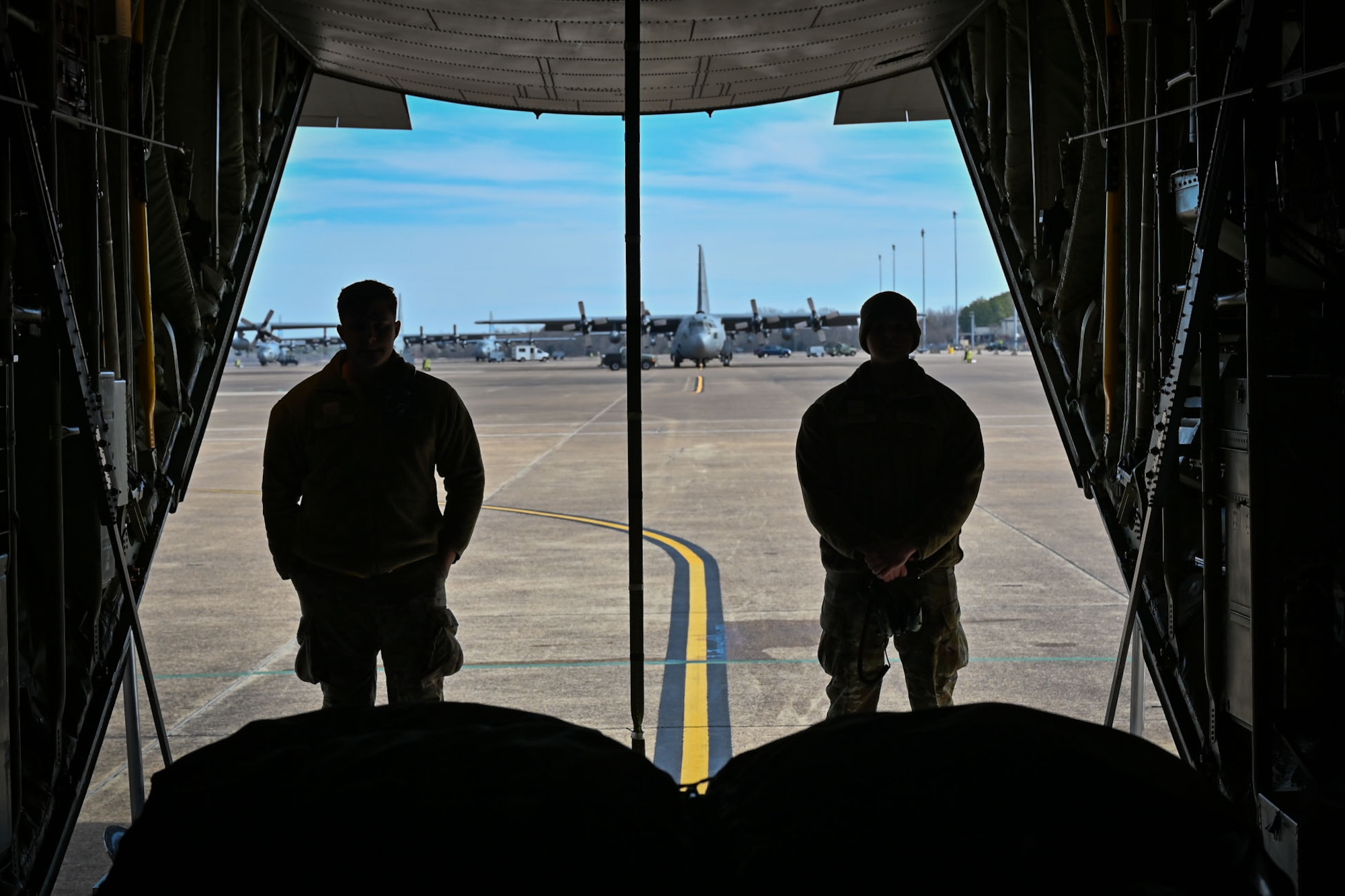 Two Airmen stand in the back of a Super Hercules aircraft
