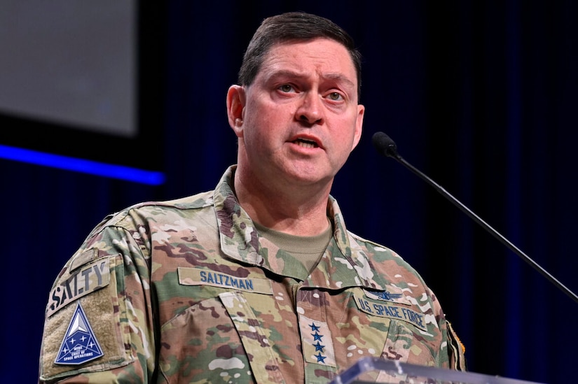 A man in uniform stands at a lectern.