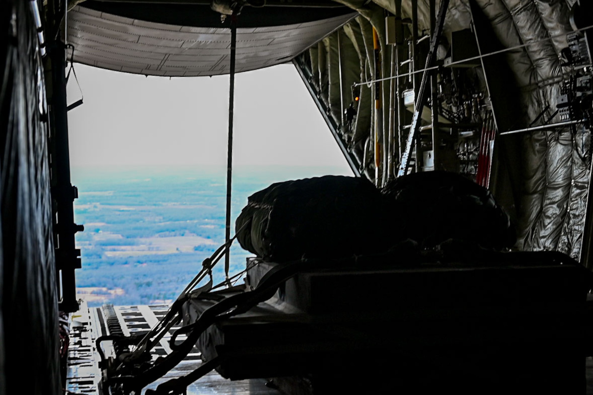 A cargo pallet sits in the back of a flying C-130J Super Hercules aircraft