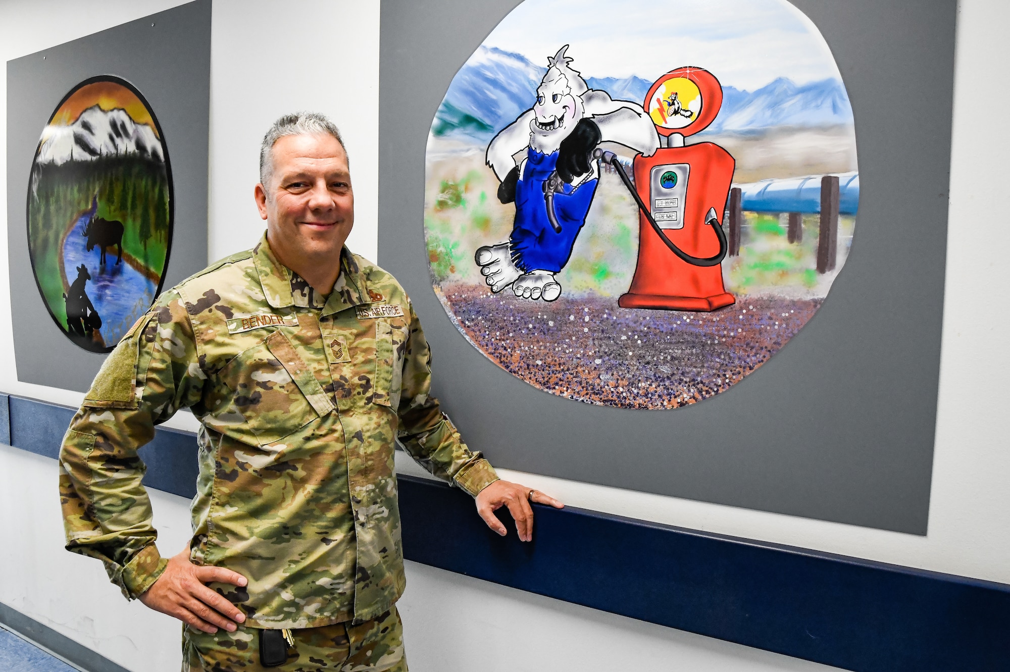U.S. Air Force Chief Master Sgt. George Bender of the 168th Wing, 168th Maintenance Group, stands in front of the 168th Wing KC-135 nose art he has drawn for the Wing’s dedicated crew chief’s aircraft and is on display in the halls of the MXG at Eielson Air Force Base.