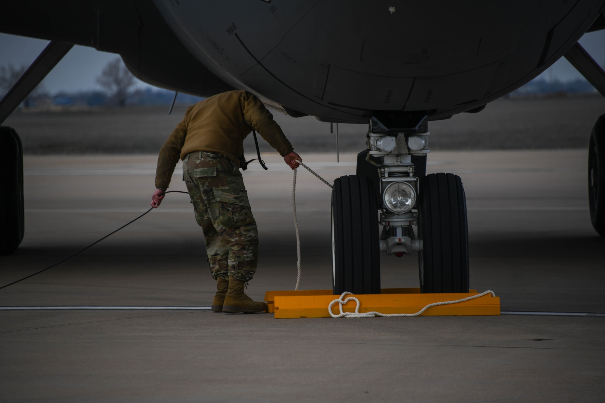 U.S. Air Force Tech. Sgt. Austin Shackelford, 190th Aircraft Maintenance Squadron (AMXS) crew chief, places a wheel chock at the wheel of a KC-135 Stratotanker at Altus Air Force Base (AFB), Oklahoma, Feb. 2, 2024. 97th Maintenance Group personnel coordinated approval for Hot Pit Refueling Permanent Site Certification at Altus AFB, providing off-site contingency training for other units to utilize. (U.S. Air Force photo by Senior Airman Miyah Gray)