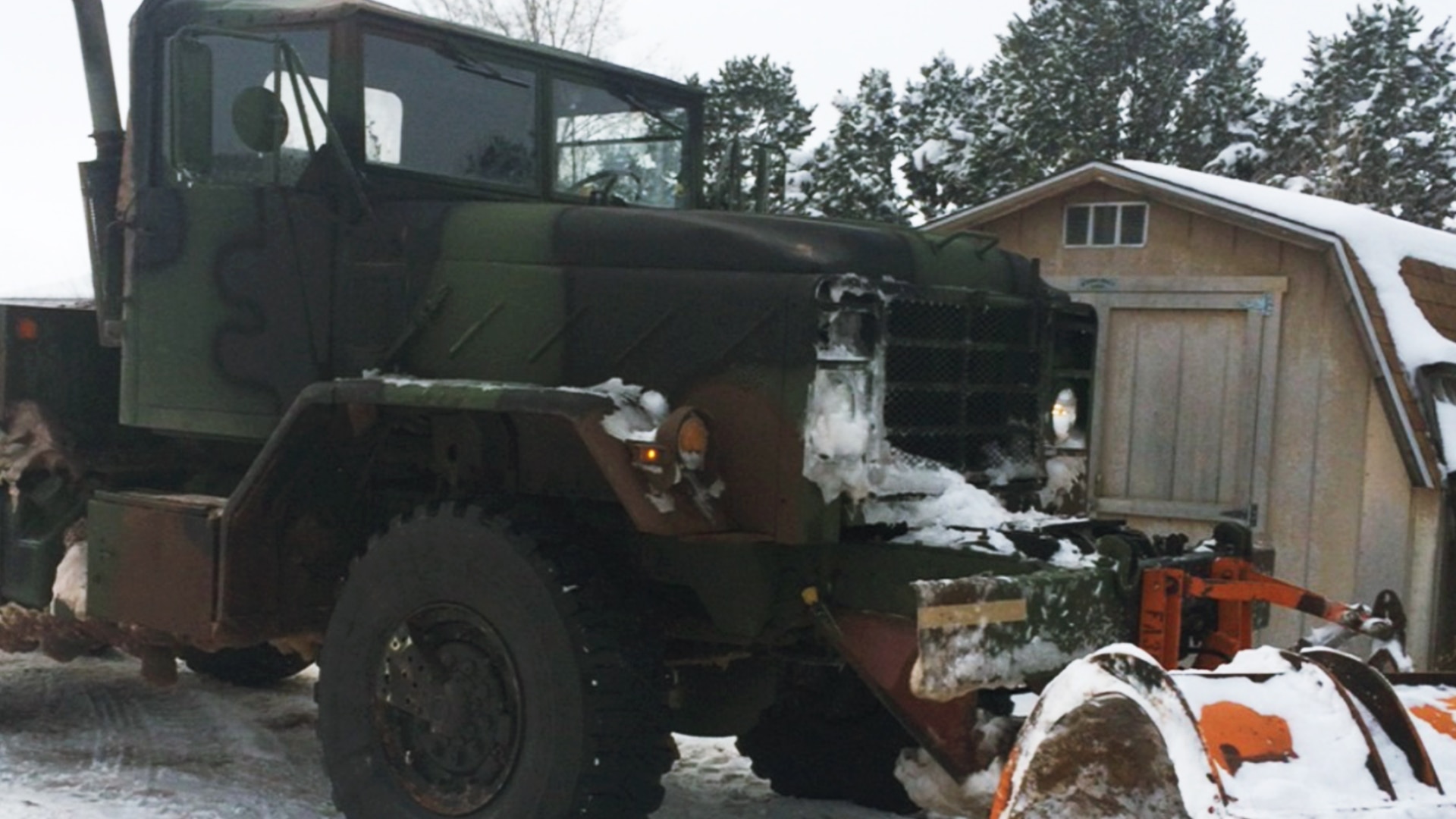 Picture of big truck with cab painted in camo sitting outdoors in the snow.