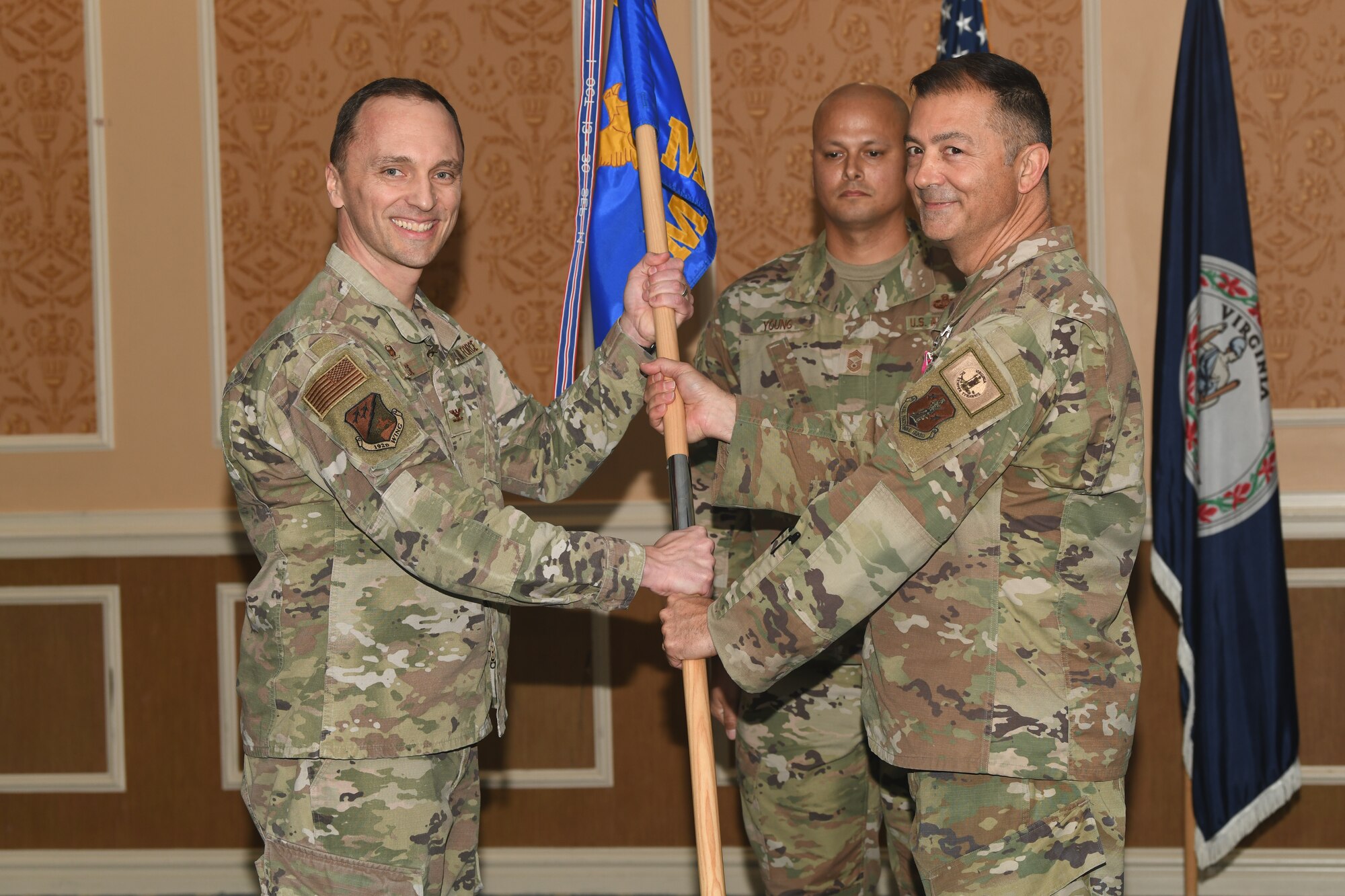 Two military members holding a guidon, smiling for photo.