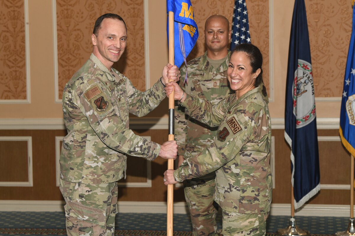 Two military members holding a guidon, smiling for photo.