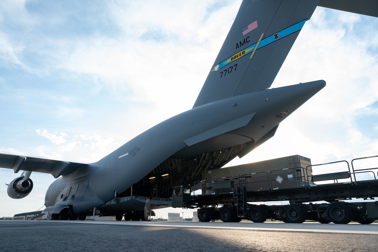 Loading equipment is staged near a military cargo plane.