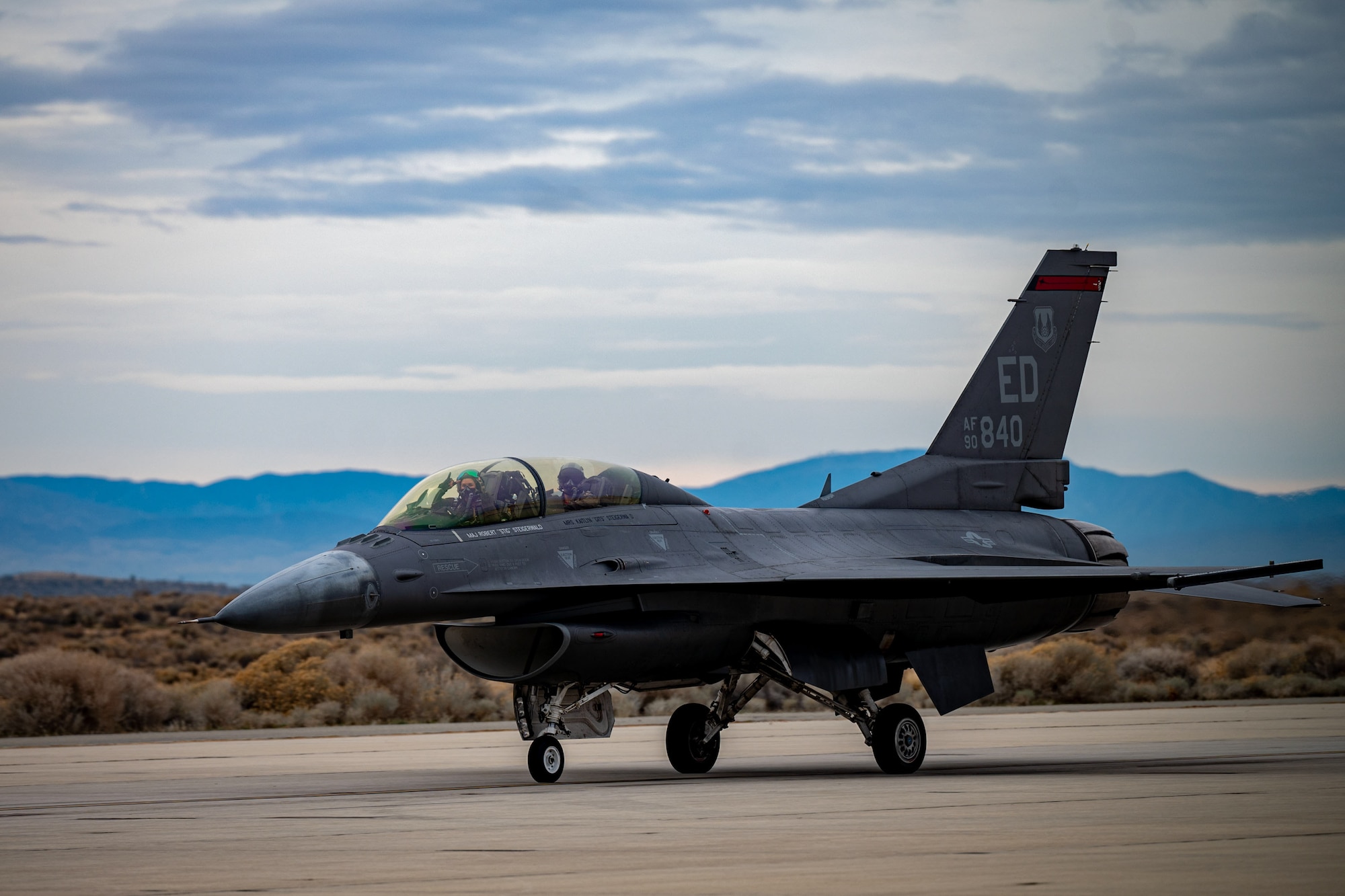 F-16 aircraft taxis with mountains in the background