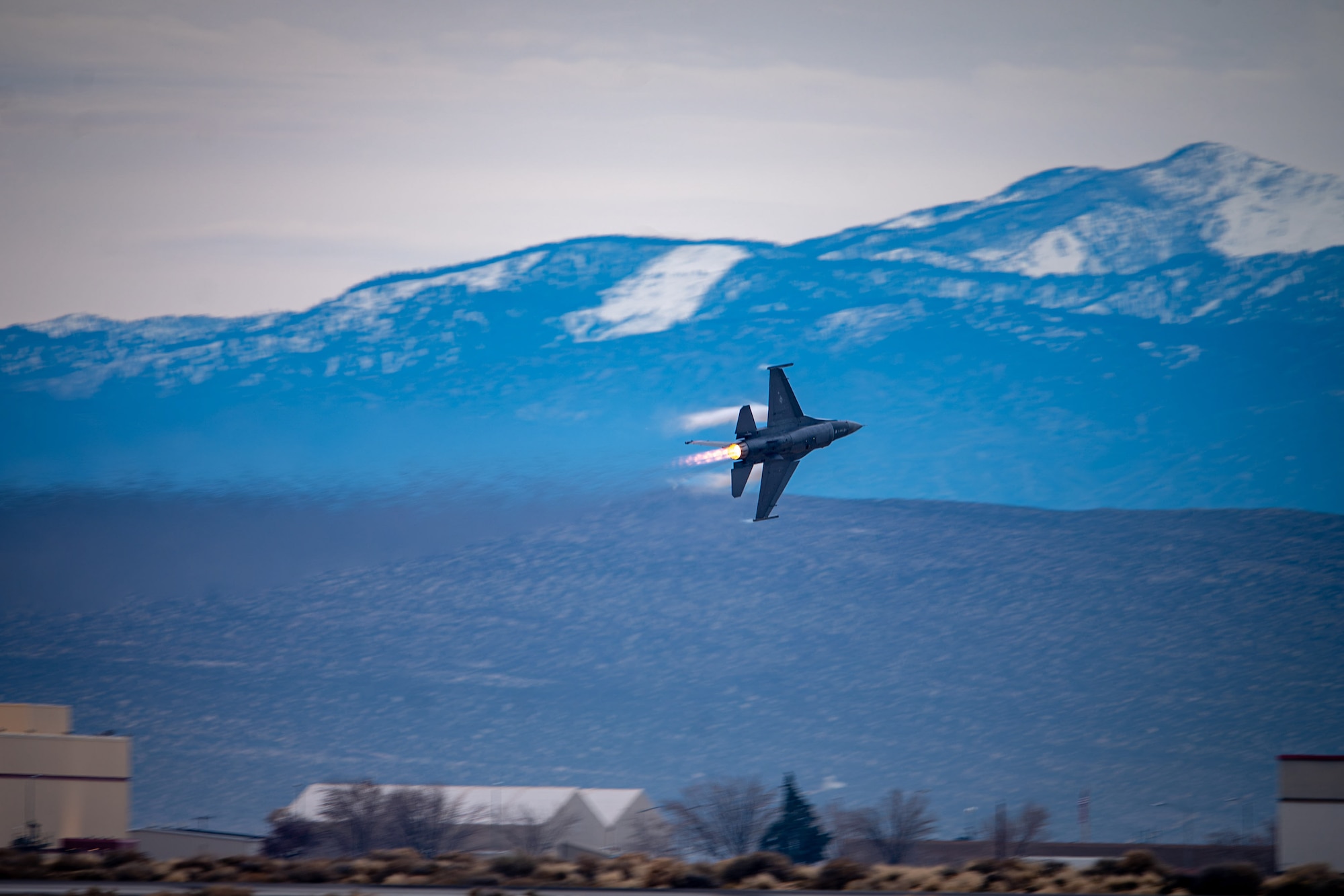 F-16 aircraft turns with mountains in the background
