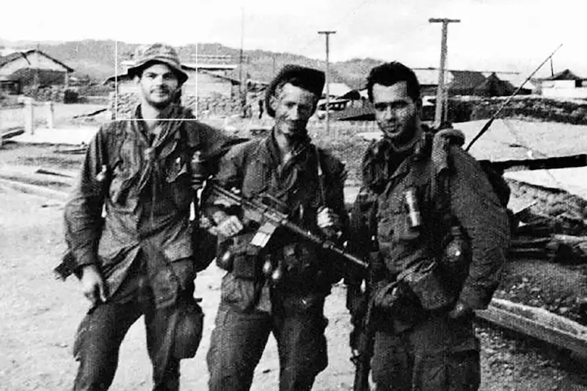 Three men in combat gear pose for a photo.