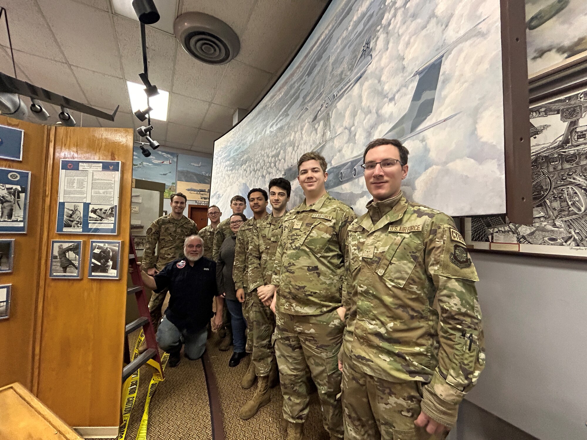 Team McChord Airmen, personnel with the 62d Airlift Wing Historian Office and McChord Air Museum volunteers stand in front of the newly restored “McChord Country Painting at Joint Base Lewis-McChord, Washington, Feb. 2, 2024. The 12-foot-long, 6-foot-high painting details various notable aircraft flying over McChord Air Force Base with Mount Rainier in the background. (U.S. Air Force Photo by Airman 1st Class Kylee Tyus)