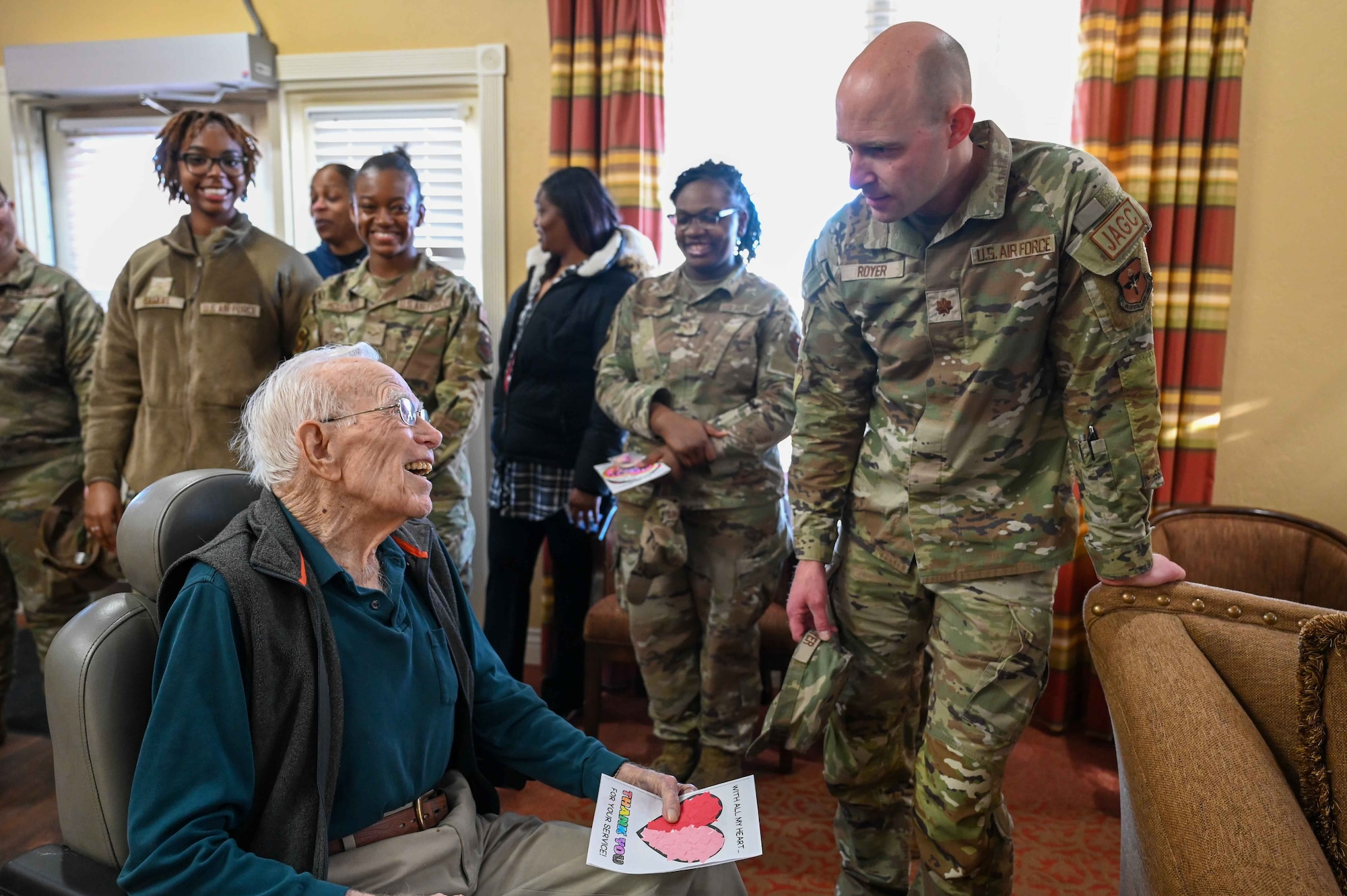Paul Kay, a former baker in the Army Air Corps, laughs with Maj. Nathan Royer, 97th Air Mobility Wing deputy staff judge advocate, at Tamarack Assisted Living Center in Altus, Oklahoma, Feb.14, 2024. Kay was drafted into the Army in 1943 and served for three years. (U.S. Air Force photo by Airman 1st Class Kari Degraffenreed)