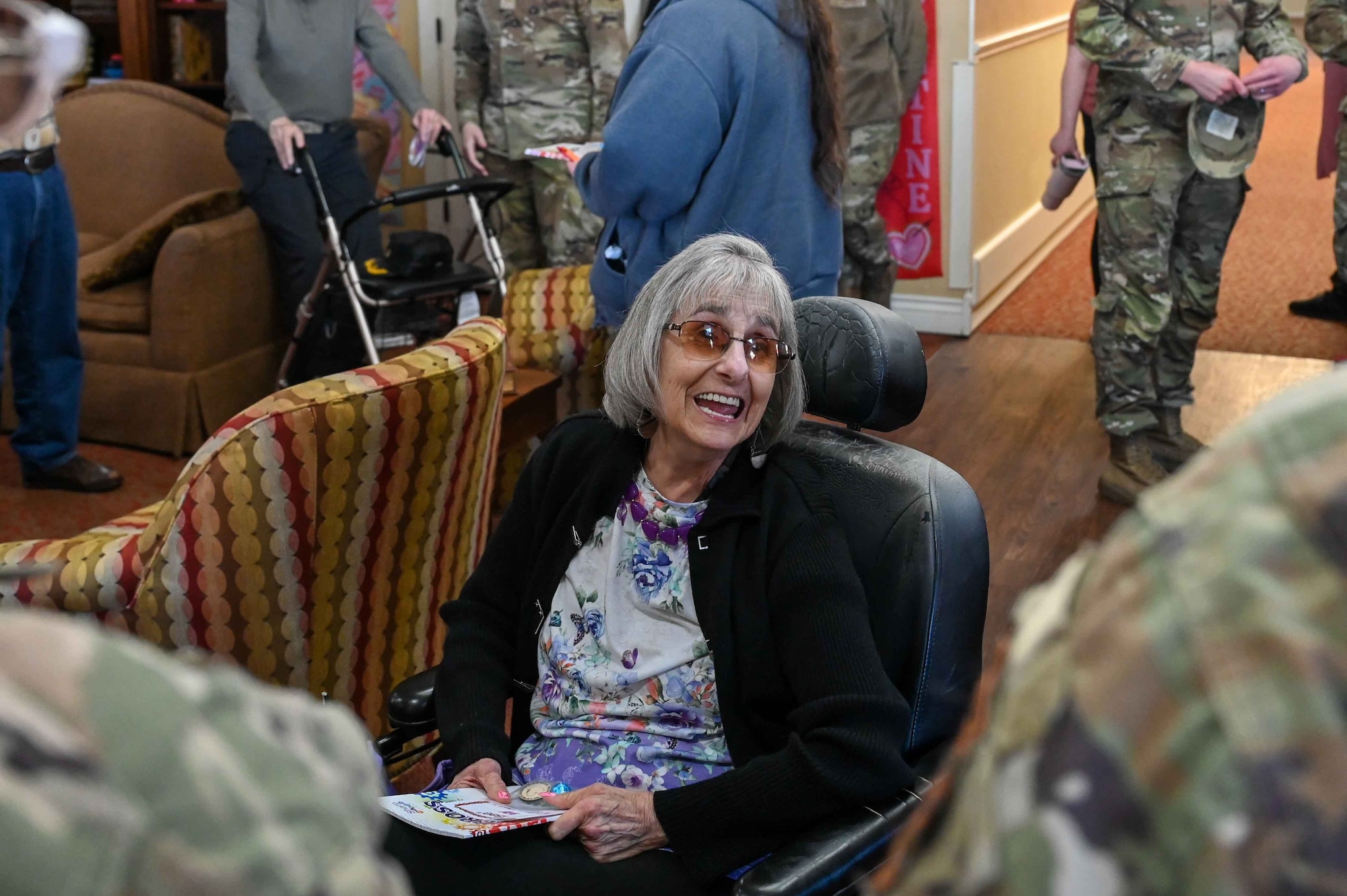 Sara McArthur, a retired Air Force Tech Sgt., smiles at the Airmen delivering Valentine's Day cards to veterans at Tamarack Assisted Living Center in Altus, Oklahoma, Feb. 14, 2024. Since she enlisted in 1979, McArthur was doing command and control until she retired in 1999. (U.S. Air Force photo by Airman 1st Class Kari Degraffenreed)