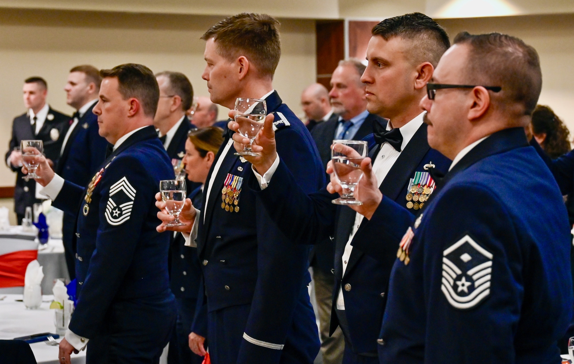 People in military tuxes hold glasses of water