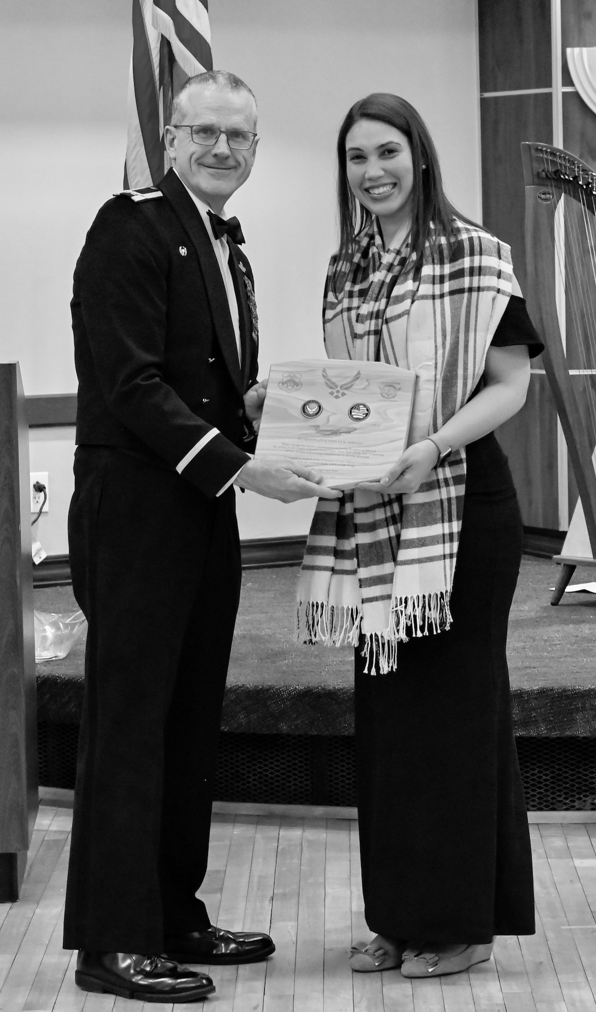 Man in military tux presenting a plaque to a woman in an evening dress